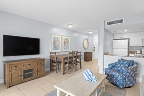 A living room with a TV, wooden furniture, a dining table, and a sofa.