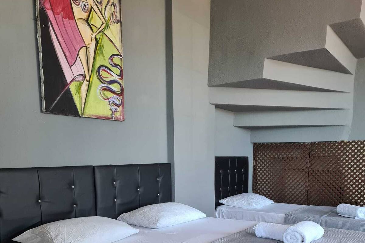 A hotel room with a large bed, two bedside tables, and a headboard with a geometric design.