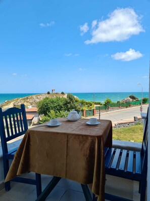 A table with a tablecloth, two chairs, and a teapot set on a balcony overlooking a coastal view. - Sword Otel (Sile)