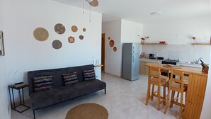 A living room with a sofa, a ceiling fan, and a kitchen with a refrigerator and a dining table. - The Yellow Flat - Sea View (Boa Vista)