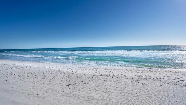 Een strand met wit zand en golven.