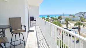 Een balkon met uitzicht op de oceaan, een stoel, een tafel en een hekwerk.