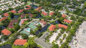 Vista aérea de uma área residencial com casas, piscina e quadra de tênis.