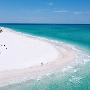 Une plage à l’eau turquoise et au sable blanc.