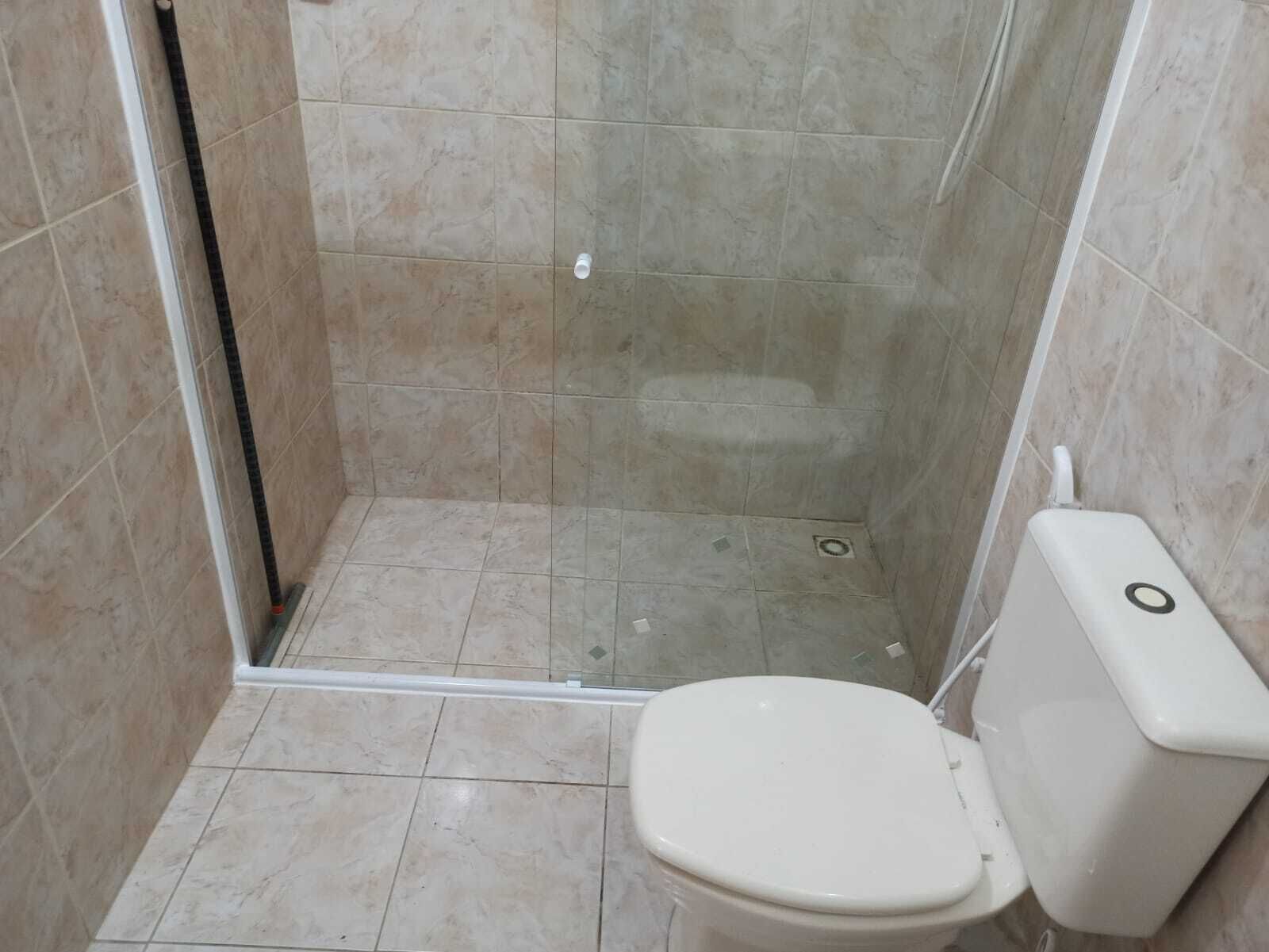 A small bathroom with a toilet, a shower stall, and tiled walls.