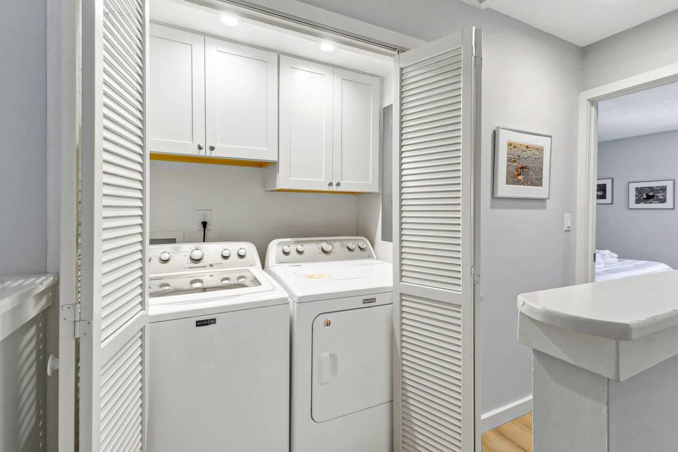 A compact laundry room with two white appliances, a white sink, and a small countertop.