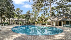 A swimming pool with a brick deck, surrounded by trees and a building with a covered area. - 162 The Greens Villa Walk to Pool, Beach (Hilton Head Island)