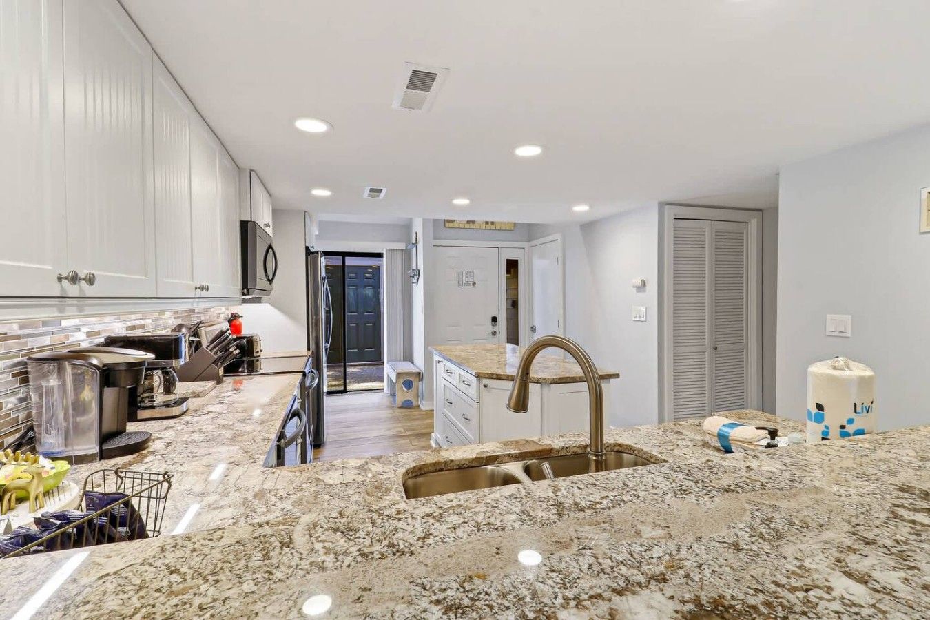 A modern kitchen with granite countertops, stainless steel appliances, and a large sink.