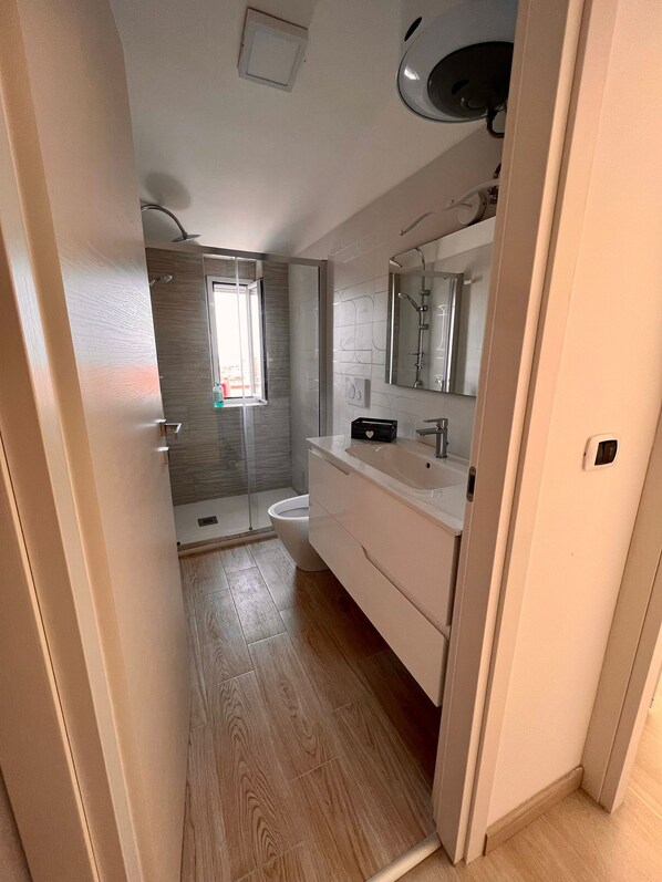 A modern bathroom with a shower, toilet, and vanity.