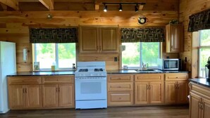 Cocina de cabaña de madera con estufa, microondas y armarios de madera.