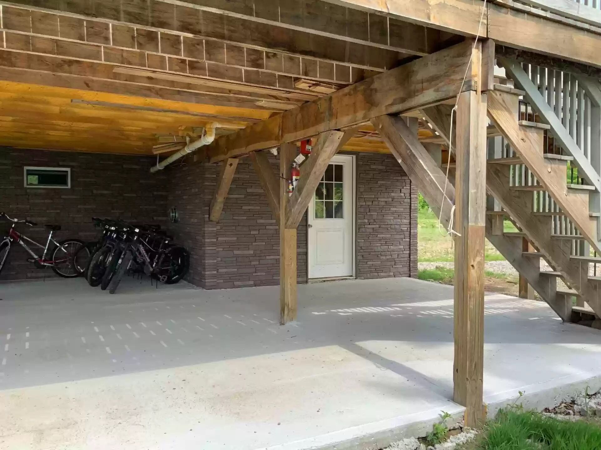 A covered outdoor area with a brick wall, a door, and a staircase.