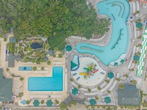 An aerial view of a resort with multiple swimming pools, a central water park, and a variety of amenities including sun loungers and umbrellas.