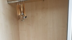 Ein Holzschrank mit einer Metallstange, an der Werkzeuge mit Holzgriffen hängen.