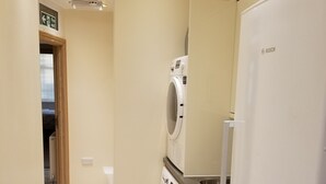 Eine kompakte Küche mit einem Kühlschrank von Bosch, einer Waschmaschine und einer Mikrowelle.