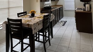 A compact kitchen with a dining table, chairs, and a stove. - Cheerful 2 Bedroom Home w/Parking in Central South Austin Pet Stays for Free ! (Austin)