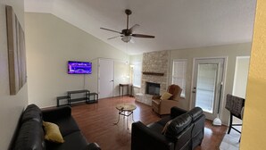 A living room with a fireplace, a ceiling fan, and a television mounted on the wall. - Cheerful 2 Bedroom Home w/Parking in Central South Austin Pet Stays for Free ! (Austin)