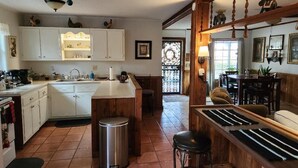 A kitchen with white cabinets, a central island, a sink, and a trash can.