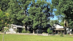 A large, open grassy area with a building featuring a porch and a covered area.