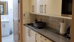 A modern kitchen with white cabinets, a stainless steel sink, and a microwave.