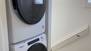 Eine übereinander gestellte Waschmaschine und ein Trockner in einem Wohnraum.