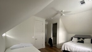 Ein Schlafzimmer mit zwei Betten, einem Deckenventilator und Holzboden.