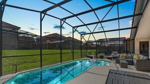 A covered outdoor pool area with a glass enclosure, a hot tub, and outdoor furniture. - Renovated villa w private pool & bbq - close to magic theme parks!! (Davenport)