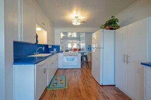 A narrow kitchen with white cabinets, a blue countertop, and a wooden floor.