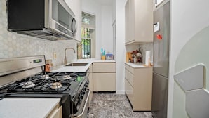 A compact kitchen with a gas stove, microwave, and stainless steel refrigerator.