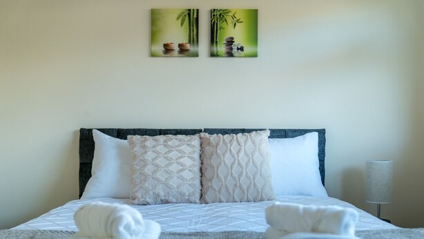 A neatly made bed with two pillows, a headboard, and a lamp on a bedside table. - Spacious Pet Friendly 2-bed Apartment in Redhill (Redhill)