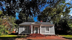 A two-story house with a front porch, a red brick driveway, and a flag. - Historic 3-bedroom Cloverdale Home next to Playhouse (Montgomery)