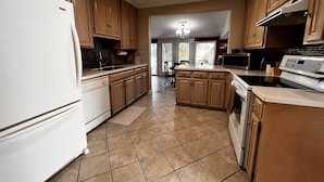A kitchen with wooden cabinets, a white refrigerator, a microwave, and a stove. - Historic 3-bedroom Cloverdale Home next to Playhouse (Montgomery)