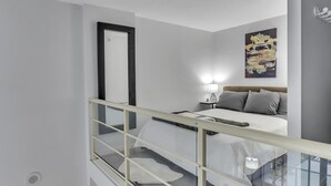 A modern bedroom with a bed, bedside table, lamp, and a wall-mounted artwork. - Modern Downtown Vancouver Loft. Parking included.  (Vancouver)