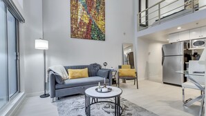 A modern living room with a grey sofa, a round coffee table, and a colorful abstract painting on the wall. - Modern Downtown Vancouver Loft. Parking included.  (Vancouver)