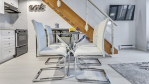 A modern kitchen with white cabinetry, a built-in stove, and a dining area with white chairs and a table. - Modern Downtown Vancouver Loft. Parking included.  (Vancouver)