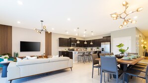 Une cuisine moderne avec des meubles de couleur sombre, un îlot central et un coin repas comprenant une table et des chaises.