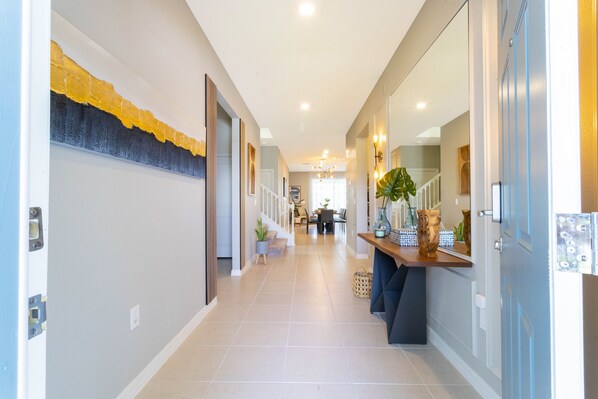 A hallway with a tiled floor, a wooden bench, and a plant.