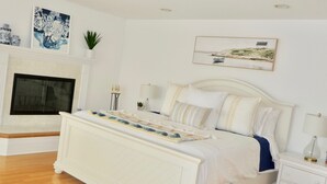 Une chambre avec un grand lit, une cheminée et un tableau au mur.