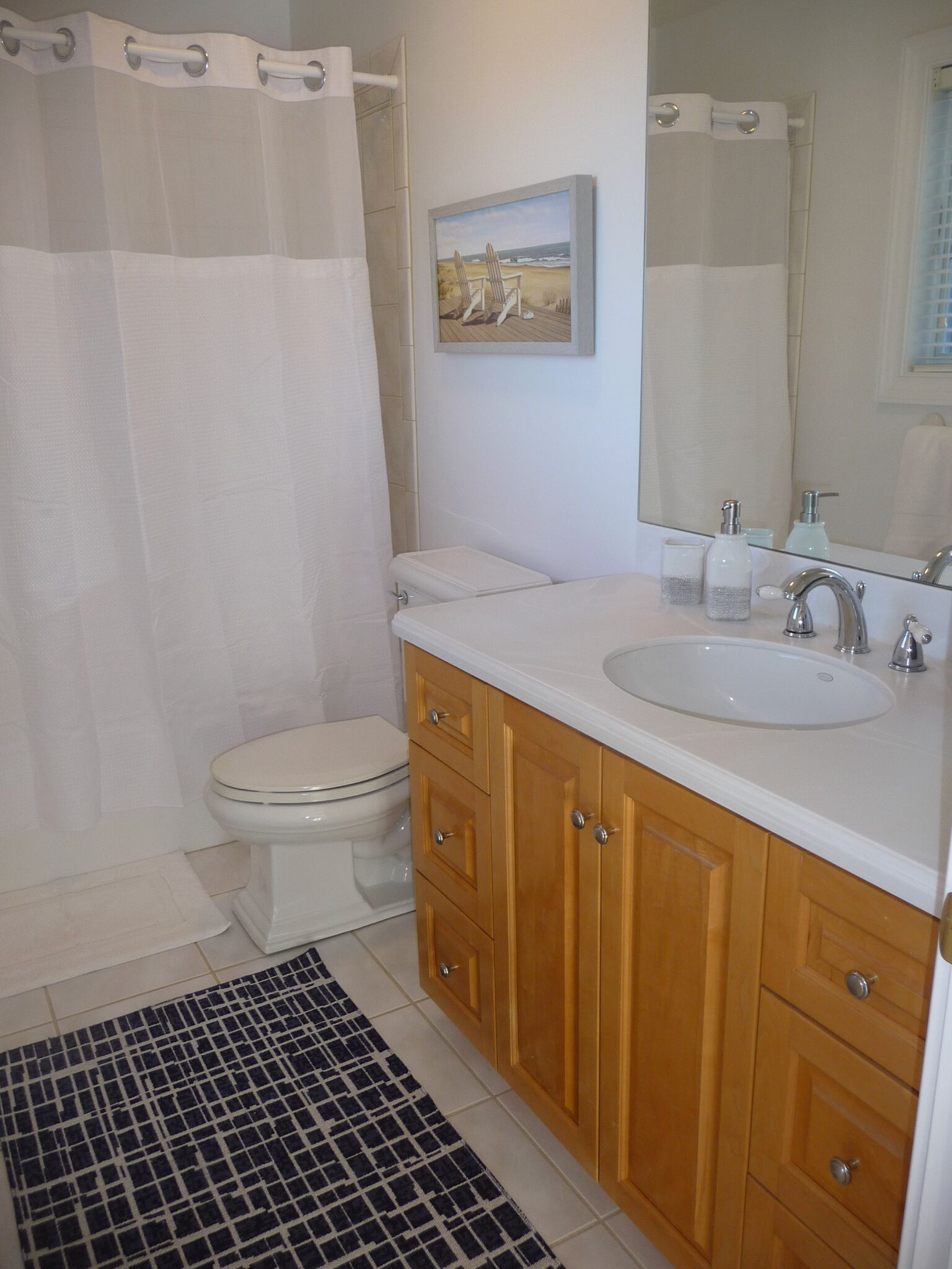 Une salle de bain comprenant des toilettes, un lavabo, des meubles en bois, un miroir et un rideau de douche.