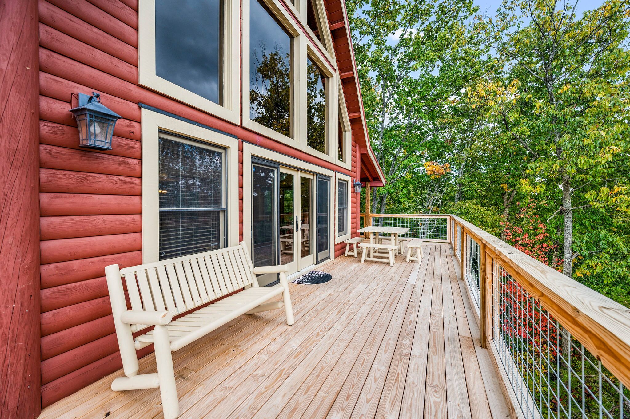 A wooden deck with a bench and table, overlooking a lush garden.