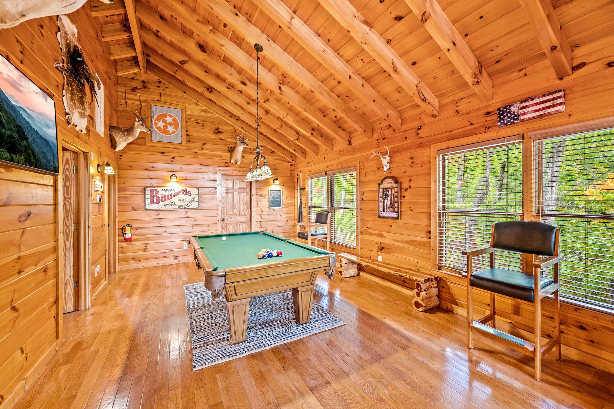 A wooden cabin interior with a pool table, a chair, and a sign reading "Billiards."
