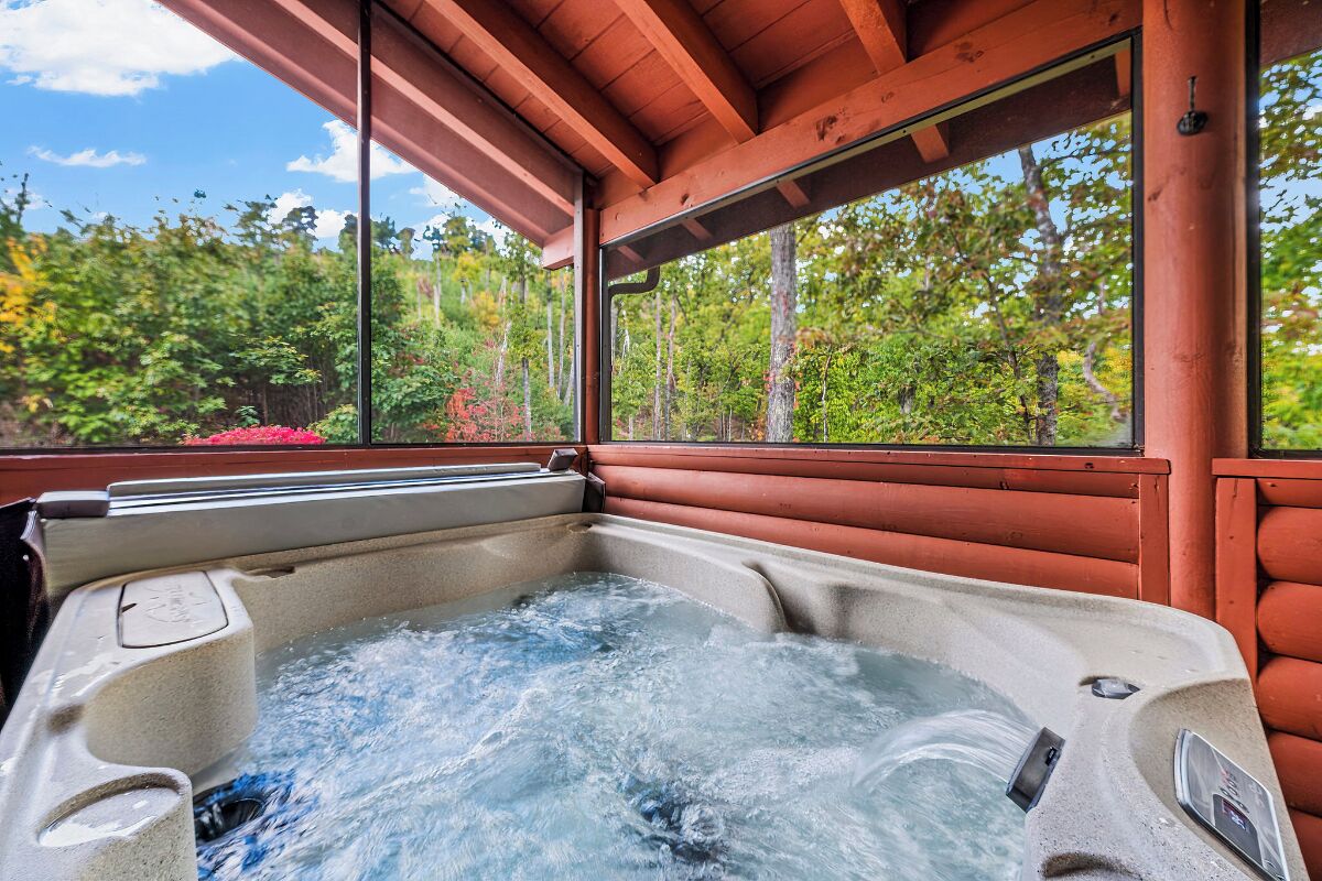Un bain à remous avec vue sur une forêt, grâce à de grandes fenêtres.