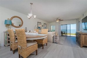 Enjoy meals at the large dining table surrounded by wicker chairs, with a view of the ocean from the large window.