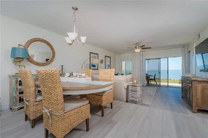 Enjoy meals at the large dining table surrounded by wicker chairs, with a view of the ocean from the large window.