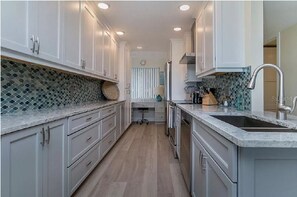 Kitchen features white cabinetry, granite countertop, and stainless steel sink.