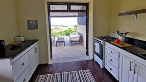 A kitchen with a view to an outdoor patio, a stove, and a sink. - Historic sea view 1 bed apartment in restored stone house (Four Hill)