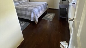 A bedroom with a bed, a nightstand, a lamp, a window with curtains, a ceiling fan, and a small table. - Historic sea view 1 bed apartment in restored stone house (Four Hill)