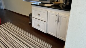 A kitchen with white cabinets, a microwave, a coffee maker, and a window. - Historic sea view 1 bed apartment in restored stone house (Four Hill)