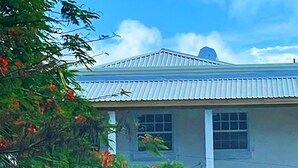 A building with a corrugated metal roof, a window, and a door. - Historic sea view 1 bed apartment in restored stone house (Four Hill)