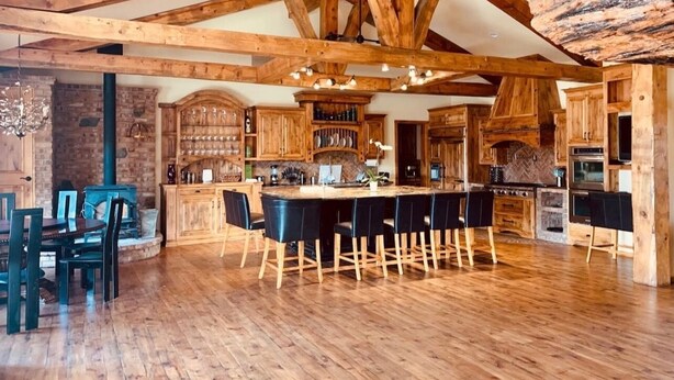 A spacious kitchen with wooden beams, a central island with bar stools, and a brick wall. - 3  🛌rooms in🐻Hot Tub🧖‍♀️ cold tank 🥶Theatre📽Library 📚Pool🎱BBQ🍔Games🎯🏀♠️🎤Gym💪 (Big Bear)