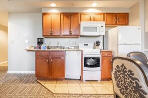 Kitchen area with microwave, refrigerator, and dishwasher, featuring a patterned rug and standard appliances.
